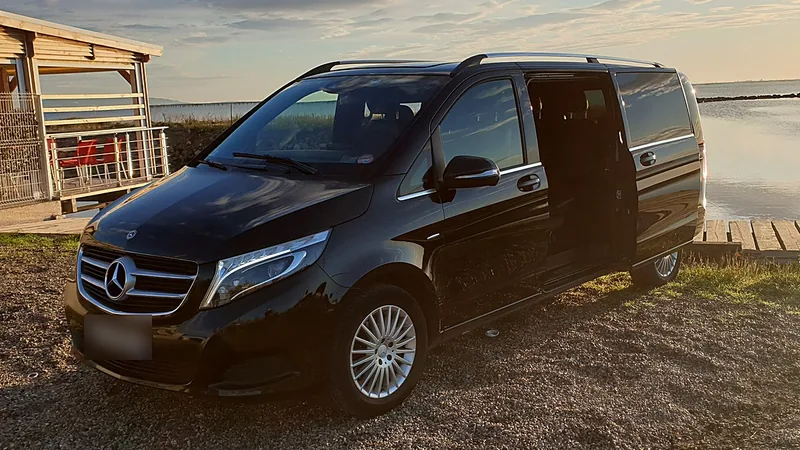 Mercedes Classe V noire, porte latérale ouverte, au bord de l'étang de Thau
